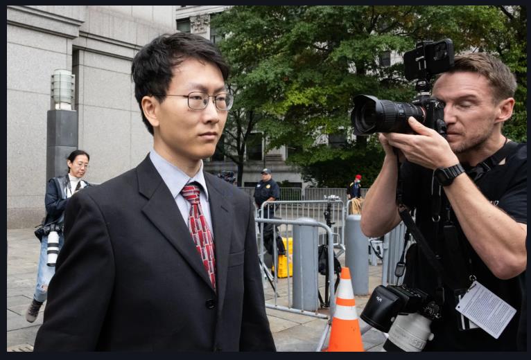 A person in a suit and tie with a cameraman taking a picture of him
Description automatically generated